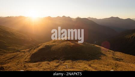 Panorama au coucher du soleil de rouge idyllique isolé montagne alpine Brewster Hut perché au sommet de la colline de l'herbe au-dessus de la vallée de la rivière Haast, West Coast SO Banque D'Images