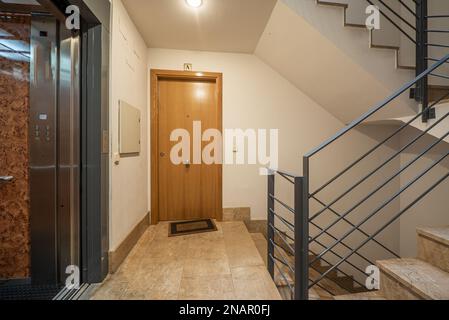 Intérieur d'un portail d'appartement résidentiel avec ascenseur avec portes en métal gris et sol en marbre crème poli, rambardes en métal gris et marbre Banque D'Images