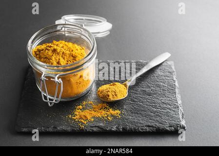 Poudre de curry (curcuma) dans un pot en verre gros plan. Mélange indien d'épices finement hachées Banque D'Images