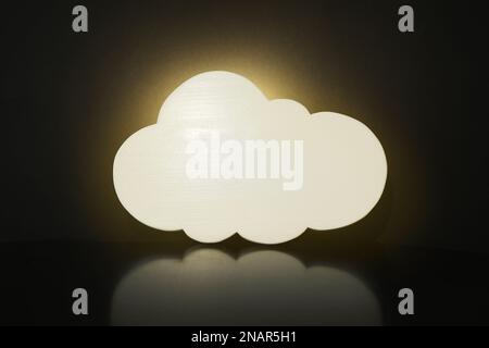 Lampe de nuit lumineuse en forme de nuage sur fond noir Banque D'Images