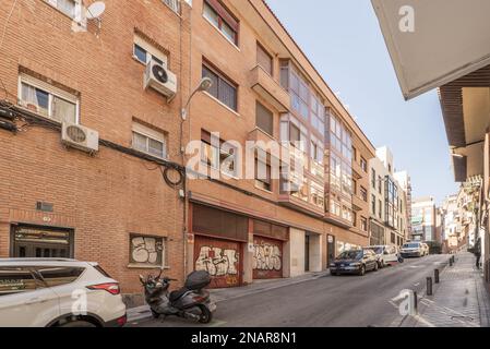 façades de bâtiments résidentiels urbains construits il y a quelques années avec des briques légères et des balcons fermés de feuilles d'aluminium et de verre sur une rue en pente Banque D'Images