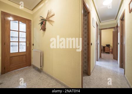 Couloir distributeur d'une maison avec sols en grès, murs peints en jaune avec portes en bois de gotelette et de chêne Banque D'Images