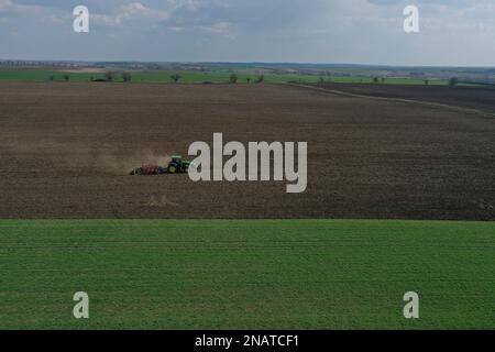 L'agriculteur travaille avec le tracteur au début de la saison de printemps. Vue aérienne du tracteur attelé pendant le travail. Banque D'Images