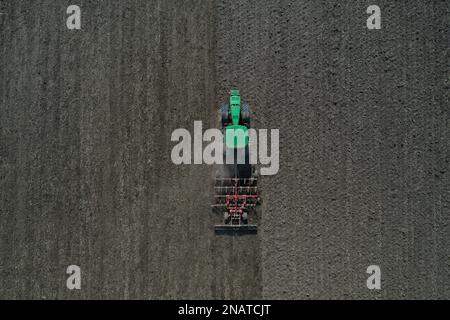 L'agriculteur travaille avec le tracteur au début de la saison de printemps. Vue aérienne du tracteur attelé pendant le travail. Banque D'Images