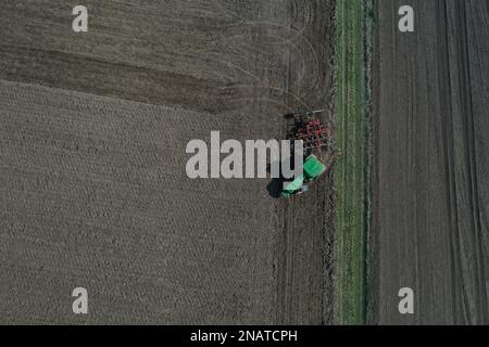 L'agriculteur travaille avec le tracteur au début de la saison de printemps. Vue aérienne du tracteur attelé pendant le travail. Banque D'Images