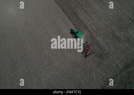 L'agriculteur travaille avec le tracteur au début de la saison de printemps. Vue aérienne du tracteur attelé pendant le travail. Banque D'Images