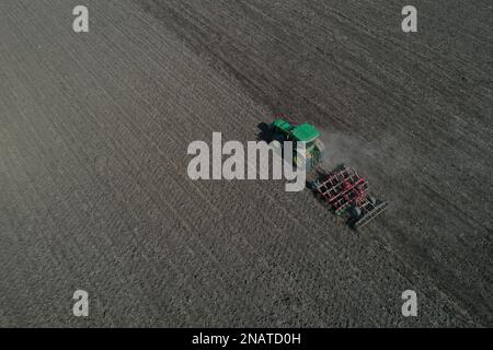 L'agriculteur travaille avec le tracteur au début de la saison de printemps. Vue aérienne du tracteur attelé pendant le travail. Banque D'Images