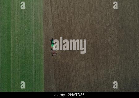 L'agriculteur travaille avec le tracteur au début de la saison de printemps. Vue aérienne du tracteur attelé pendant le travail. Banque D'Images