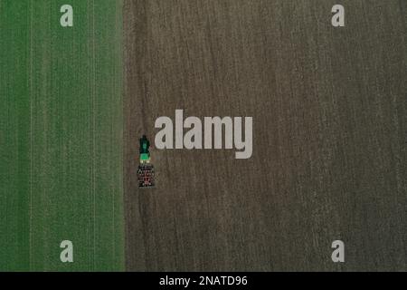 L'agriculteur travaille avec le tracteur au début de la saison de printemps. Vue aérienne du tracteur attelé pendant le travail. Banque D'Images