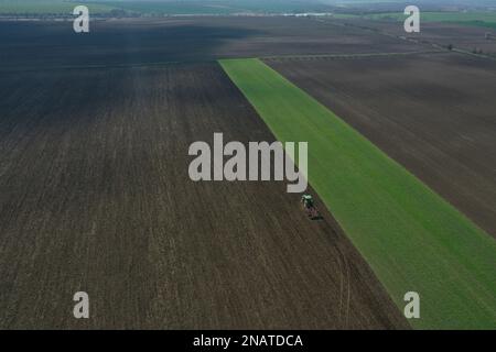 L'agriculteur travaille avec le tracteur au début de la saison de printemps. Vue aérienne du tracteur attelé pendant le travail. Banque D'Images