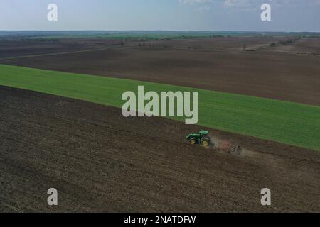 L'agriculteur travaille avec le tracteur au début de la saison de printemps. Vue aérienne du tracteur attelé pendant le travail. Banque D'Images