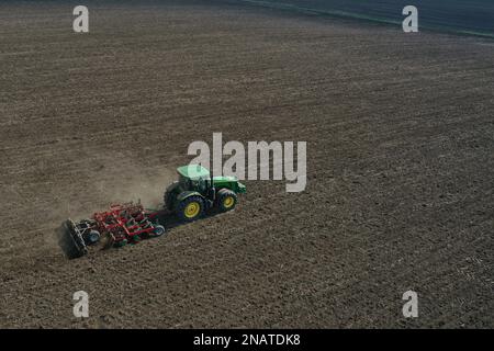 L'agriculteur travaille avec le tracteur au début de la saison de printemps. Vue aérienne du tracteur attelé pendant le travail. Banque D'Images