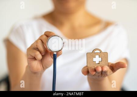 Concept des personnes et de la santé. Gros plan de femme main tenant stéthoscope avec sac en bois diecut avec logo de croix médicale. Banque D'Images