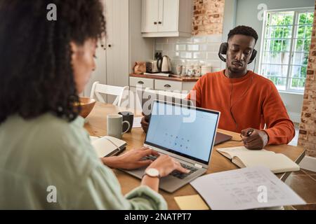 Jeune couple multiracial travaillant à distance en ligne à partir de chez lui Banque D'Images