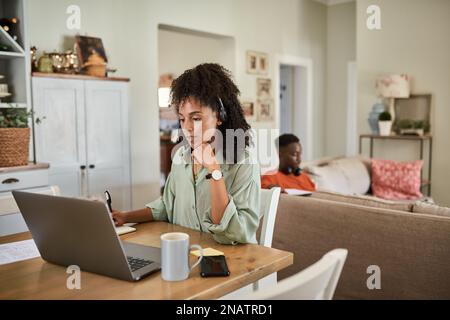 Une jeune femme africaine en communication tout en travaillant à distance de chez elle Banque D'Images