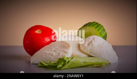 Fromage mozzarella de Buffalo avec un peu de salade isolée sur un fond de gradient frais. Banque D'Images