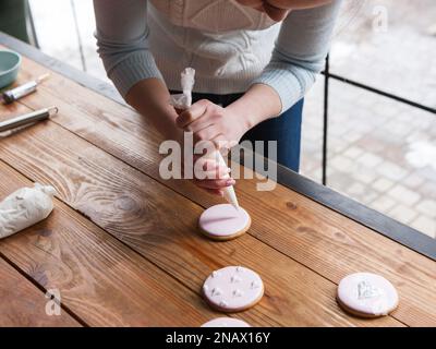 Femme chef décorant du pain d'épice avec de la crème Banque D'Images