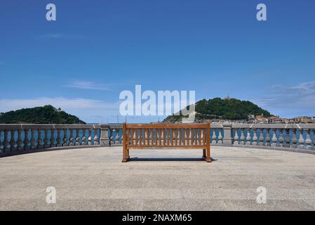 Banc vide d'un point de vue sur la plage de la Concha. Vide, espace vide, ciel bleu clair avec nuages, architecture , Donosti, Espagne Banque D'Images