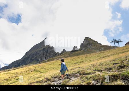 Sentier de randonnée de Mannlichen à Wengen, Suisse alpes, scène de nuages géants tombant dans une vallée, ouverture de l'embouchure de la montagne. Jeune enfant marchant. Banque D'Images