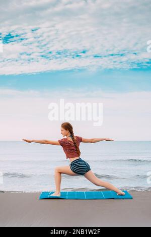 Active Sport redhead femme faisant du yoga sur la plage au Monténégro vue latérale, Femme est dans les vêtements de sport à la plage de la mer Adriatique Banque D'Images