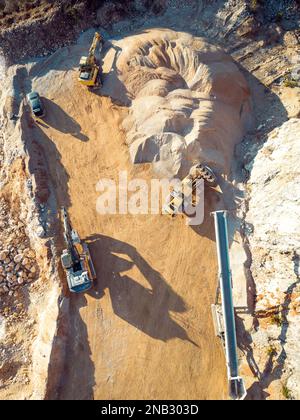 Photo verticale de machines lourdes jaunes, excavatrices travaillant sur des carrières poussiéreuses Banque D'Images