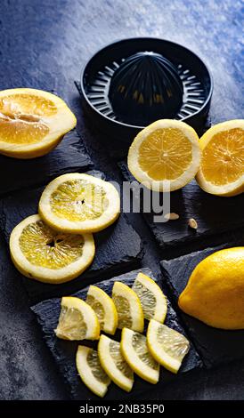 Design élégant de fond de citrons et de tranches de citron avec presse-fruits et couteau sur ciment noir ou foncé ou surface en pierre.vue du dessus avec espace de copie. Banque D'Images