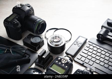 Station de travail photo numérique sur fond blanc.vue du dessus de l'appareil photo numérique, du flash, de l'objectif et de l'ordinateur portable.Equipement photographique professionnel. Banque D'Images