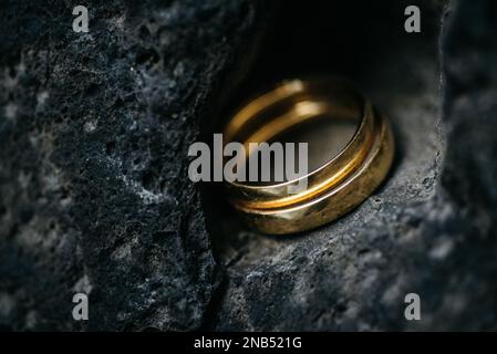 Un gros plan des anneaux dorés de mariage sur la pierre avec un arrière-plan flou Banque D'Images