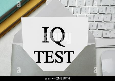 Papier avec mots IQ Test dans enveloppe et clavier sur table de bureau, plat Banque D'Images