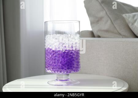 Différentes couleurs de remplissage dans vase en verre sur table blanche à la maison. Perles d'eau Banque D'Images