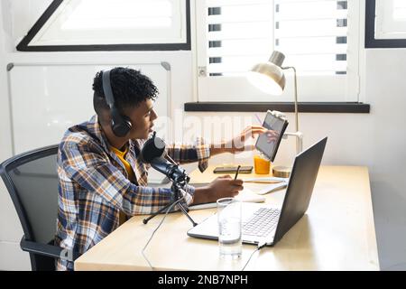 Adolescent afro-américain avec casque, microphone et podcast d'enregistrement sur ordinateur portable. Adolescent, adolescence, passe-temps et passer du temps libre à la maison. Banque D'Images