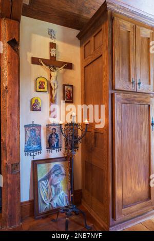 Crucifix, icônes religieuses sur le mur et candélabres en plus de forme carrée armoire en bois antique dans la chambre principale à l'étage à l'intérieur de la vieille maison de 1826. Banque D'Images