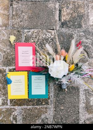 Les invitations multicolores sont situées sur les pavés à côté du bouquet de mariage Banque D'Images