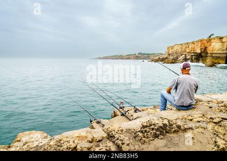 Cascais, Portugal, 27 octobre 2016: Un homme pêche au large de la côte clify près de Cascais, Portugal Banque D'Images