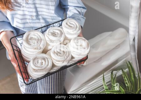 Les mains de la femme mettent ou présentent une serviette blanche enroulée propre en coton biologique. Banque D'Images