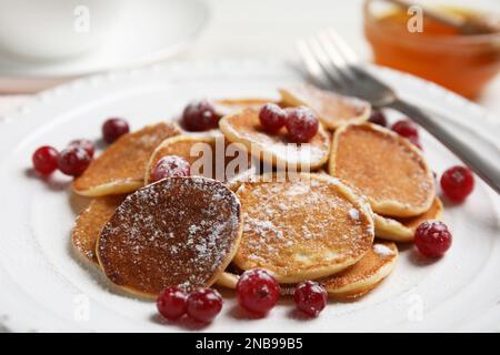 Délicieux mini crêpes aux céréales avec canneberges dans l'assiette, gros plan Banque D'Images