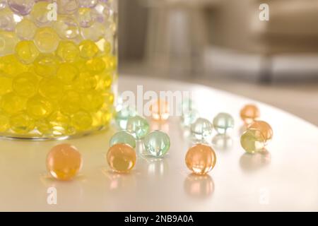 Différentes couleurs de remplissage et vase en verre sur table blanche dans la chambre, gros plan. Perles d'eau Banque D'Images