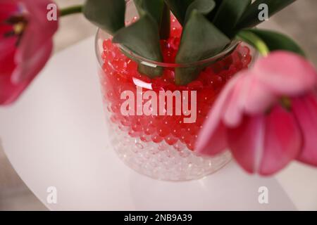 Garnitures et tulipes de différentes couleurs dans vase en verre, gros plan. Perles d'eau Banque D'Images