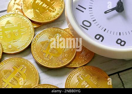 Réplique de bitcoin doré et horloge de table sur fond de bois blanc. Concept commercial et financier. Banque D'Images