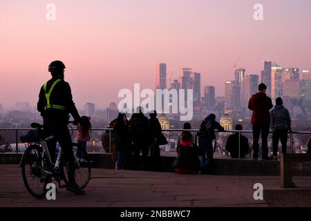 Londres, Royaume-Uni. 13th février 2023. Un cycliste regarde la vue depuis Greenwich Park. Des conditions brumeuses ont été observées à Greenwich Park au coucher du soleil et au crépuscule, car des vents du sud devraient amener des dépôts de poussière sahariennes au Royaume-Uni, qui culmineront entre mardi et mercredi. La poussière minérale dans l'atmosphère peut transformer le ciel d'une teinte orange, causer des pluies de sang et des levers et couchers de soleil spectaculaires. Crédit : onzième heure Photographie/Alamy Live News Banque D'Images