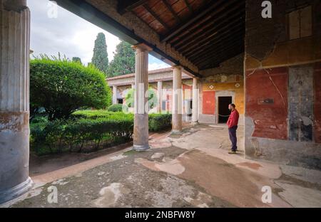 Un touriste donne sur le jardin depuis les murs extérieurs couverts rouges de feesco à la villa Praedia di Giulia Felice. Au parc archéologique de Pompéi près de Na Banque D'Images