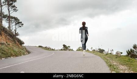 La course devient rythmique. Prise de vue en longueur d'une femme méconnue qui fait du jogging seul à l'extérieur. Banque D'Images