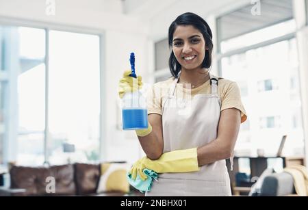 La saleté n'a pas le temps de s'installer dans ma maison. une jeune femme utilisant des gants en caoutchouc et un désinfectant pour nettoyer sa maison. Banque D'Images