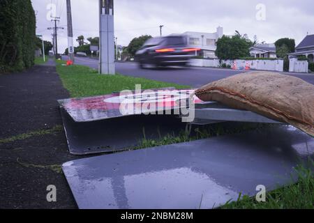 Sac de sable sur le dessus d'un panneau de route 50km tombé pour l'empêcher de s'échapper par le vent puissant de cyclone. Voiture hors-focus qui se déplace sur la rade. Auckland. Banque D'Images