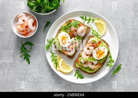 Toast avec crevettes, guacomole d'avocat, arugula et œuf dur, vue du dessus Banque D'Images