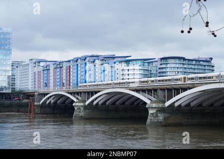 Nouveaux blocs d'appartements derrière le pont ferroviaire Grosvenor sur la Tamise à neuf Elms, Londres, Angleterre, lors d'une journée d'hiver terne. Banque D'Images