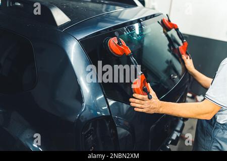 Travailleur remplaçant le pare-brise d'une voiture dans une station-service Remplacement du pare-brise. Photo de haute qualité. Banque D'Images