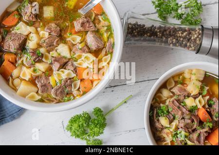 Soupe de nouilles de bœuf avec bouillon transparent, légumes-racines et pâtes dans un bol. Cuisine allemande Banque D'Images