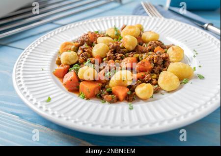Ragoût de bœuf haché avec pois, carottes et gnocchi sur une assiette Banque D'Images