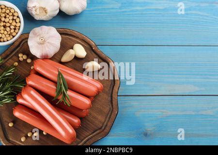 Saucisses végétariennes fraîches et légumes crus sur une table en bois bleu clair, plat. Espace pour le texte Banque D'Images